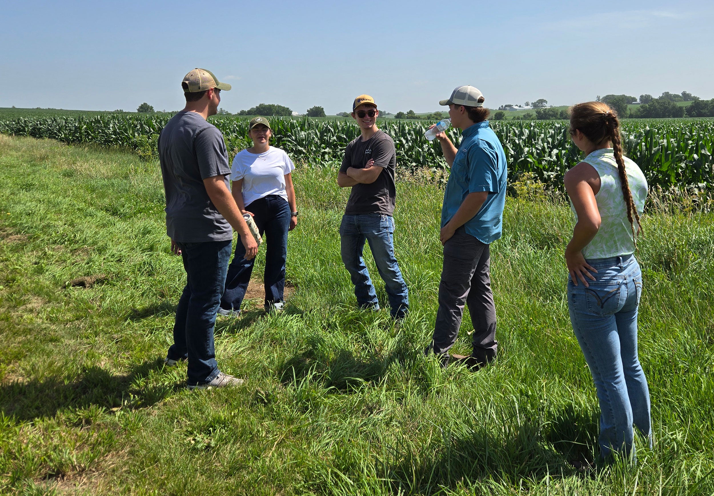 Agriculture students gathered beside a corn field.